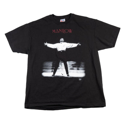 Black t-shirt with a graphic of a person on stage and 'Manilow' text, on a white background