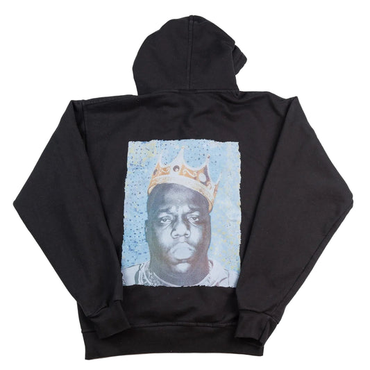 Black hoodie with a graphic of a person wearing a crown on the back, displayed against a white background.