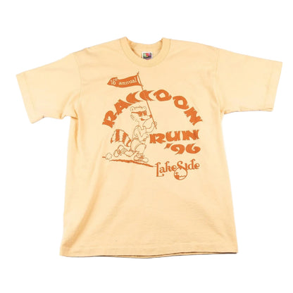Beige t-shirt with raccoon graphic and text on a white background